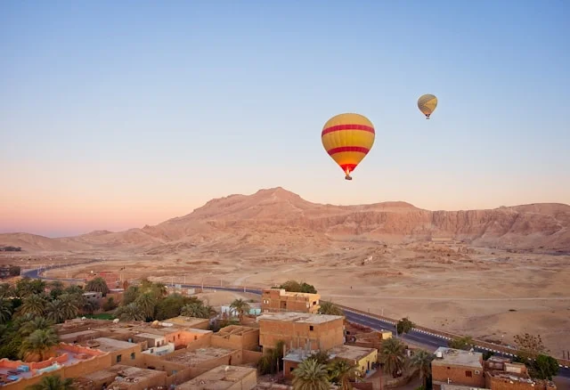 Montgolfière survolant des maisons et des montagnes