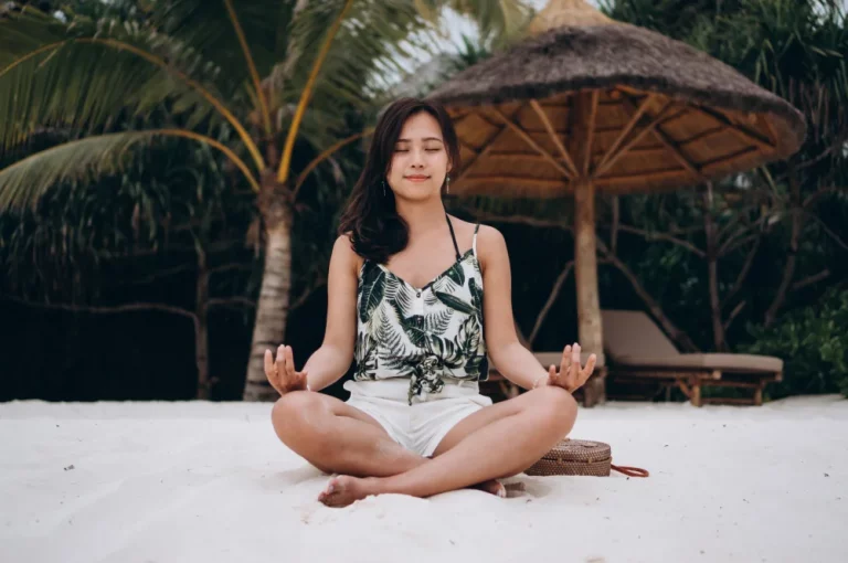 Femme asiatique pratiquant le yoga sur la plage