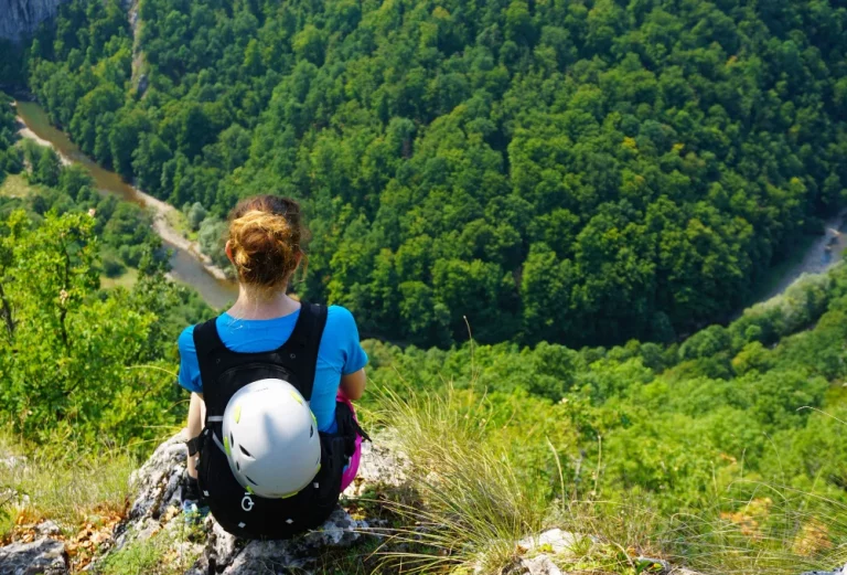 Randonneuse assise au bord d'une falaise regardant la forêt en contrebas