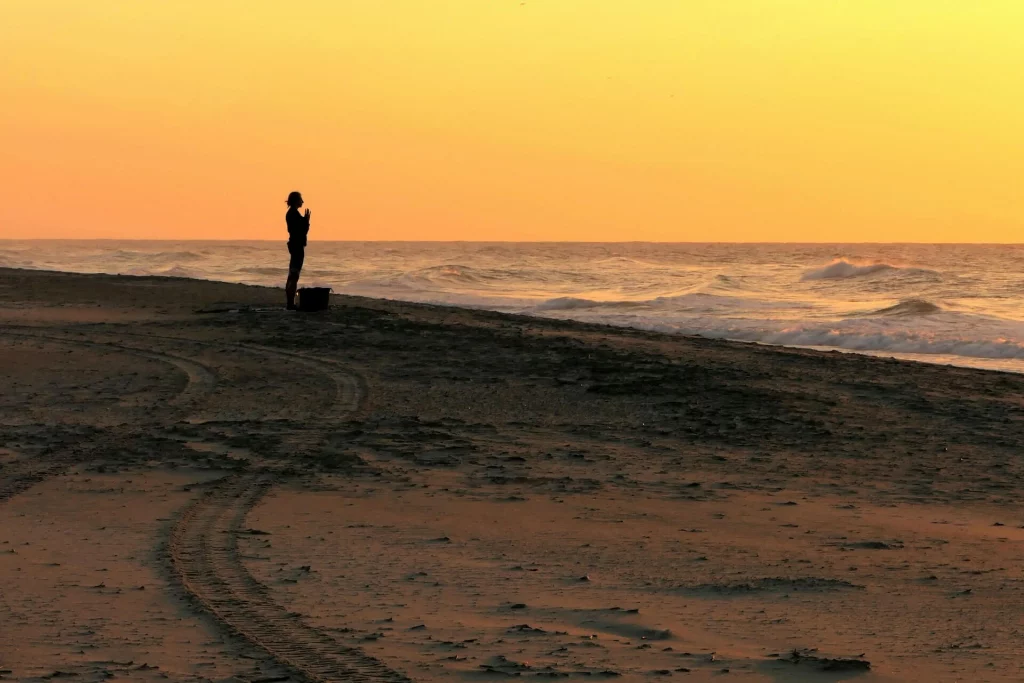 Femme méditant au lever du soleil sur la plage