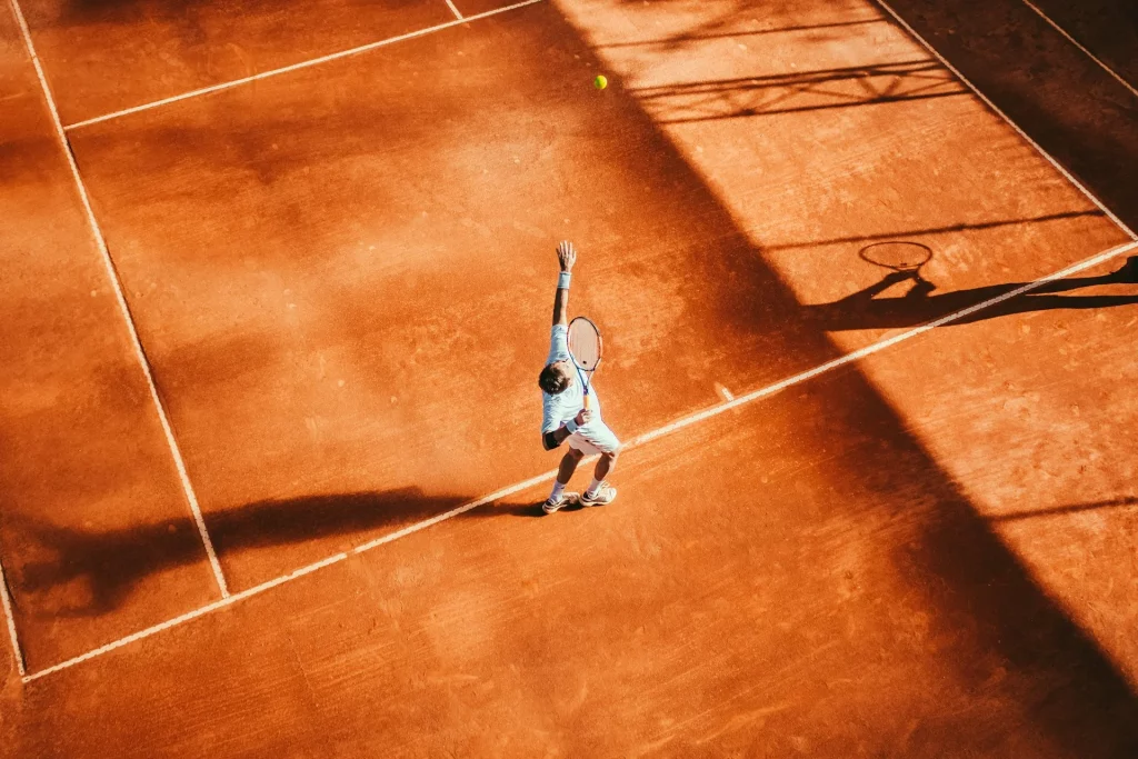 Service de tennis sur un court en terre battue.