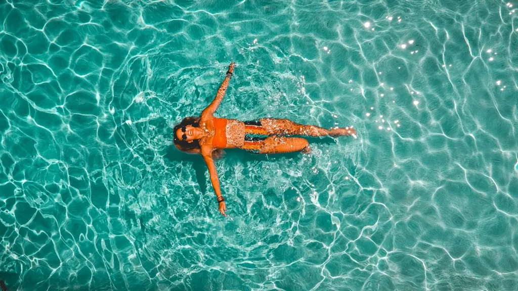 Femme flottant dans une piscine d'eau cristalline.