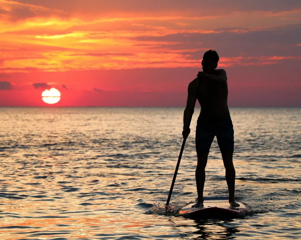 Homme en silhouette faisant du paddleboard pendant l'heure dorée