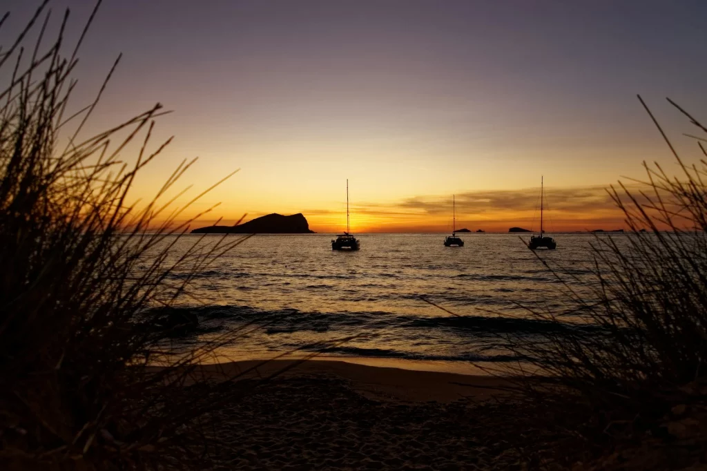 Coucher de soleil à Ibiza avec des voiliers ancrés dans des eaux calmes