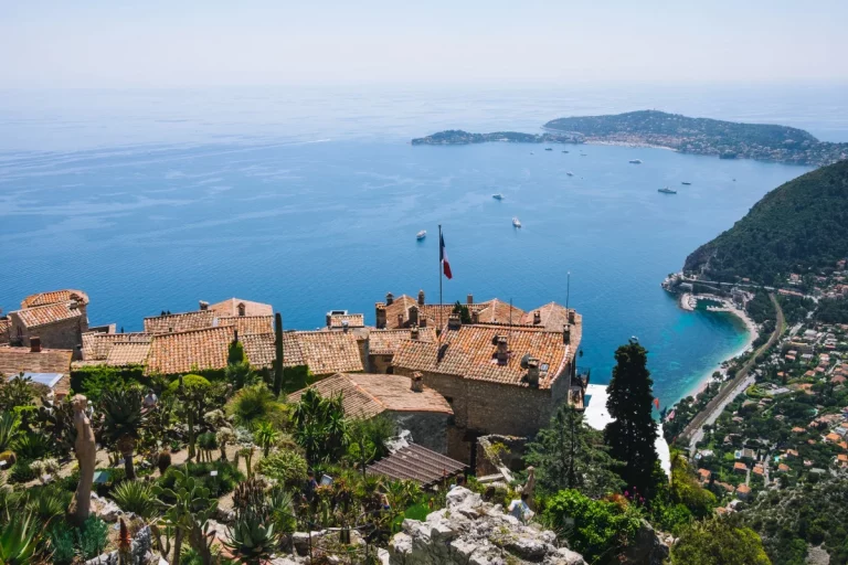 Le village d'Èze perché sur une colline, entouré par la mer Méditerranée, avec ses toits en terre cuite et sa végétation luxuriante.