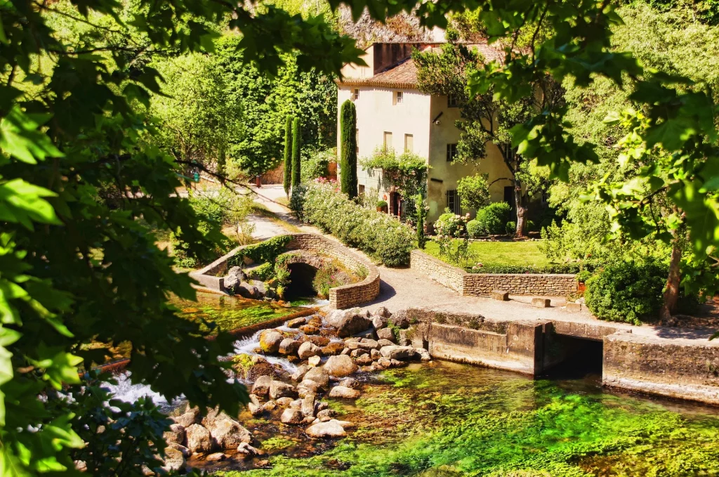 Paysage provençal avec des champs verdoyants et une rivière sinueuse traversant une vallée ensoleillée.