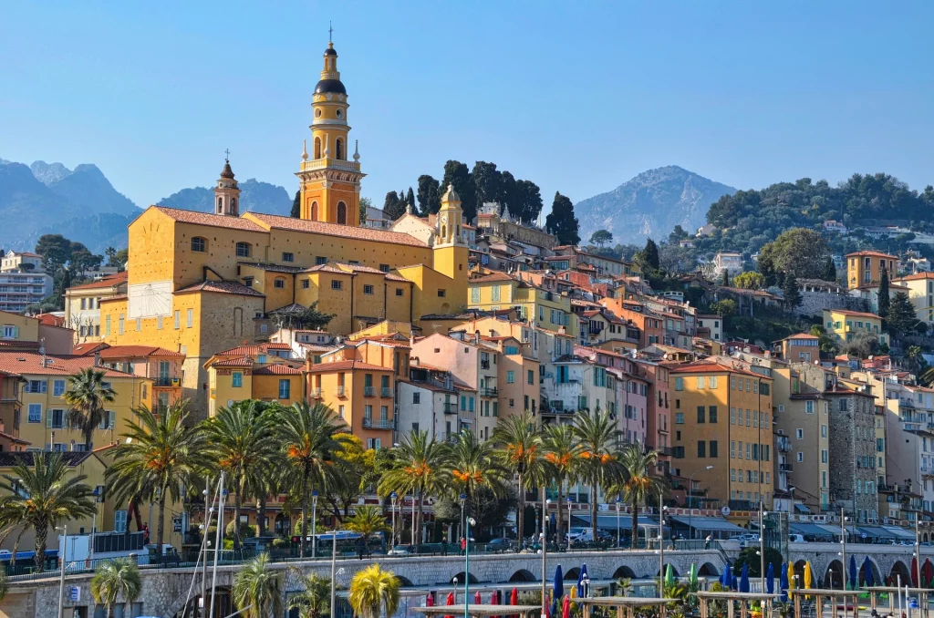 Vue sur les bâtiments colorés de Menton, avec des façades lumineuses et des toits en terre cuite, typiques de la Côte d'Azur.