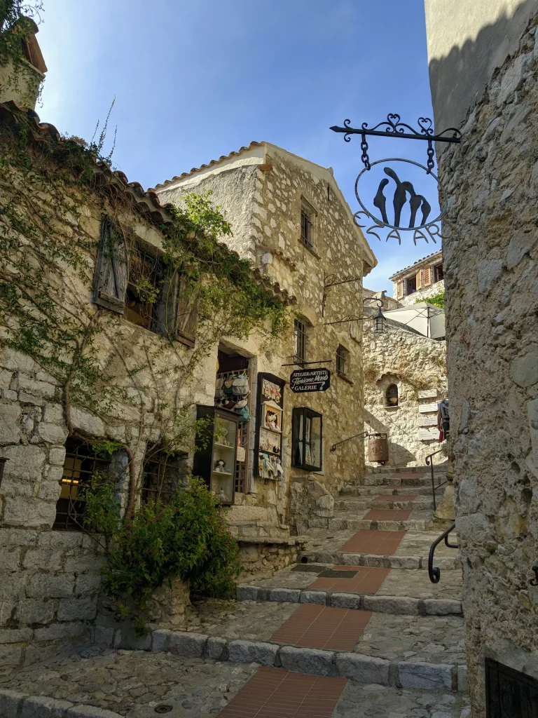 Vue du village médiéval d'Èze perché sur une colline, entouré par la végétation luxuriante et offrant une vue imprenable sur la mer Méditerranée.