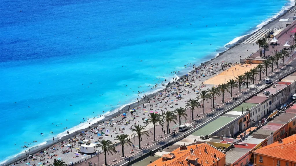 Vue de l'eau cristalline de la mer Méditerranée à Nice, France, avec des nuances de bleu éclatantes sous un ciel clair.