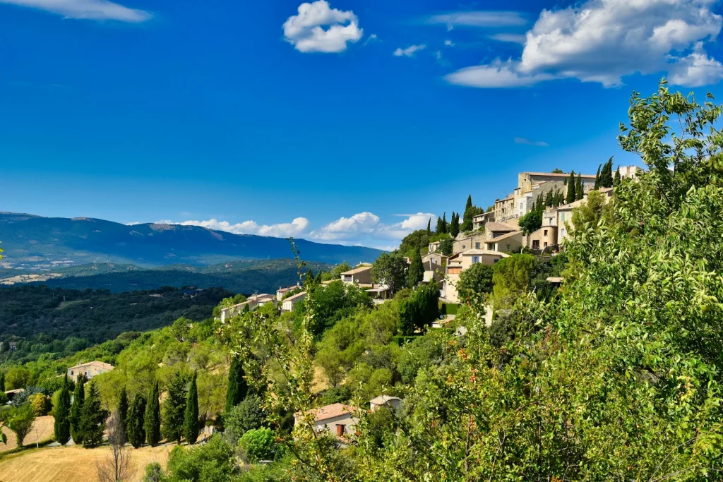 Vue panoramique sur les collines verdoyantes de Lurs, un village pittoresque en Provence, avec des champs et des paysages naturels à perte de vue.